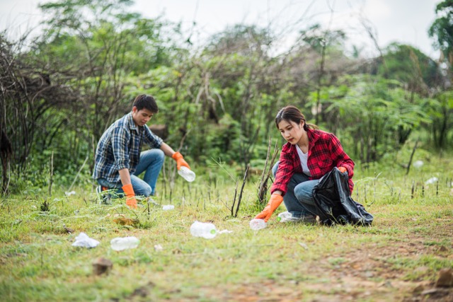 Men and women help each other to collect garbage.