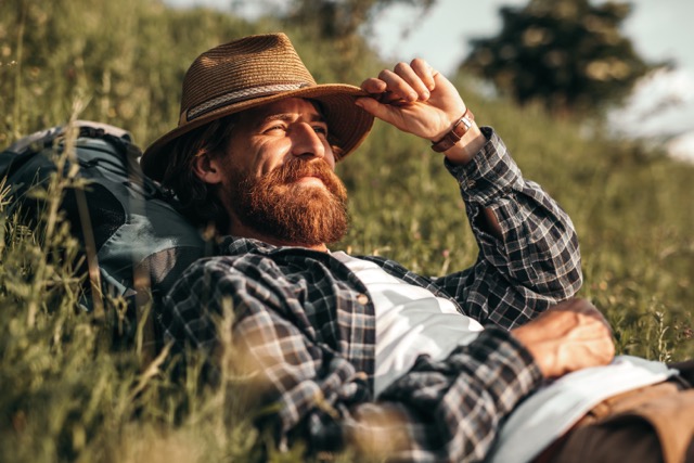 relaxed-male-backpacker-lying-on-grass-taking-rest-2022-11-12-03-06-25-utc Medium