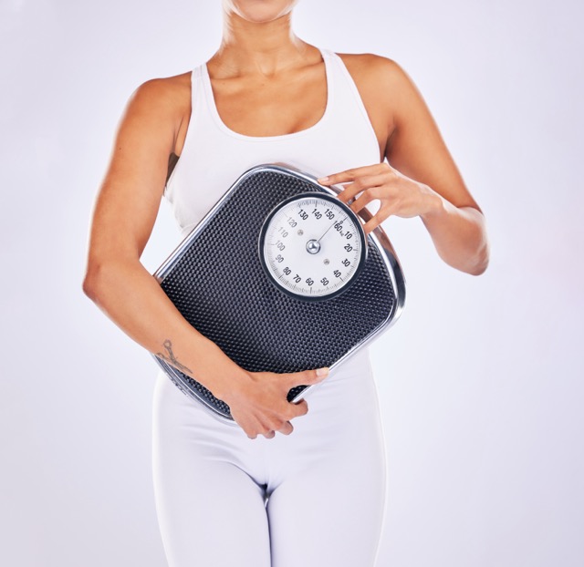 Hand holding scale, woman and studio for wellness, motivation and body positive by background. Girl