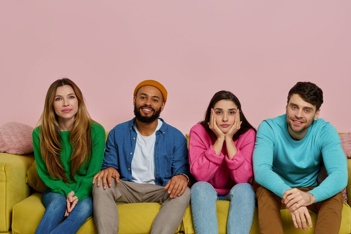 Studio shot of young people looking at camera while sitting on the couch together