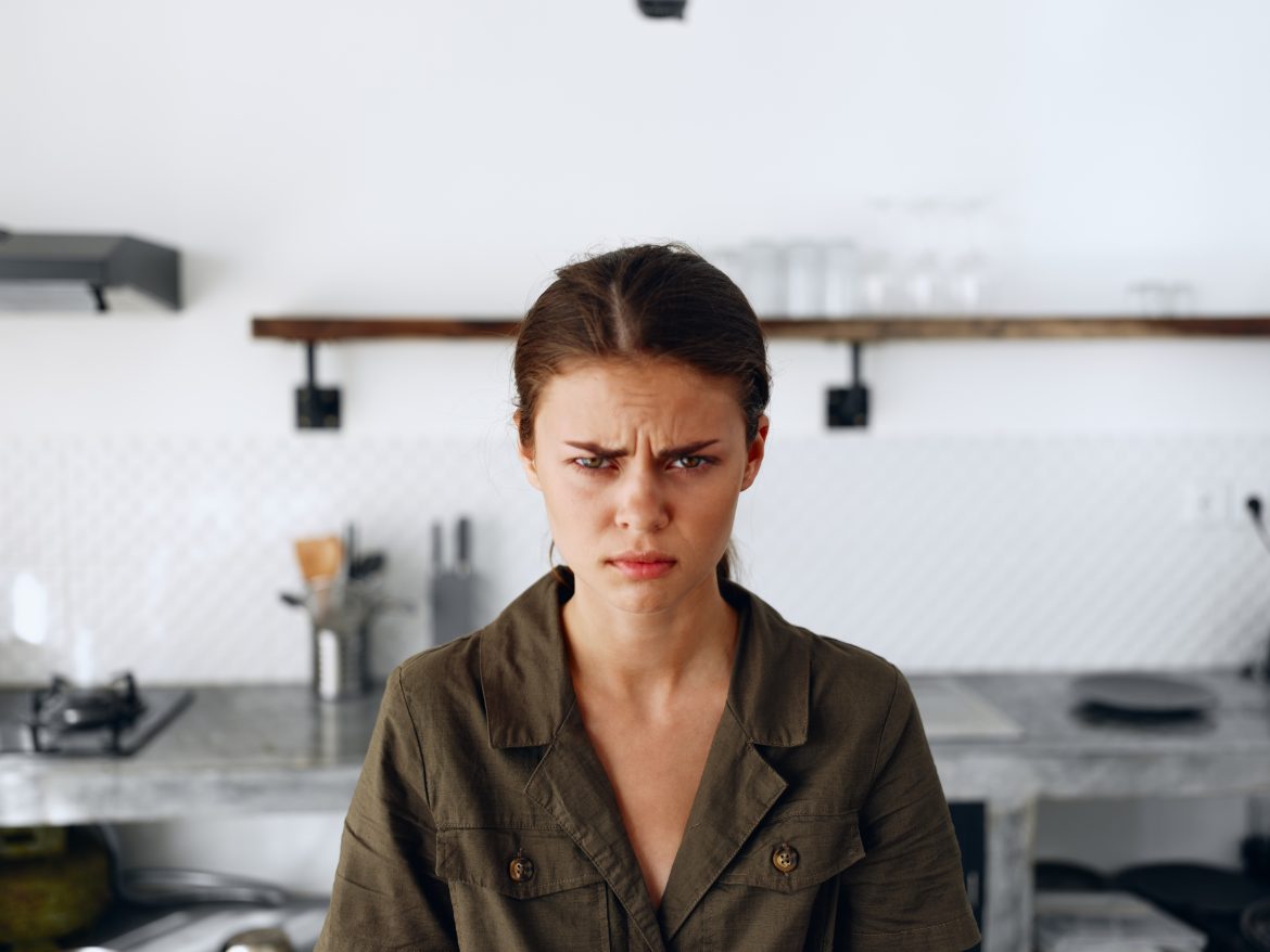 Portrait of a sad tired woman with a sore head in the kitchen, domestic problems, unstable emotional state, onion tears